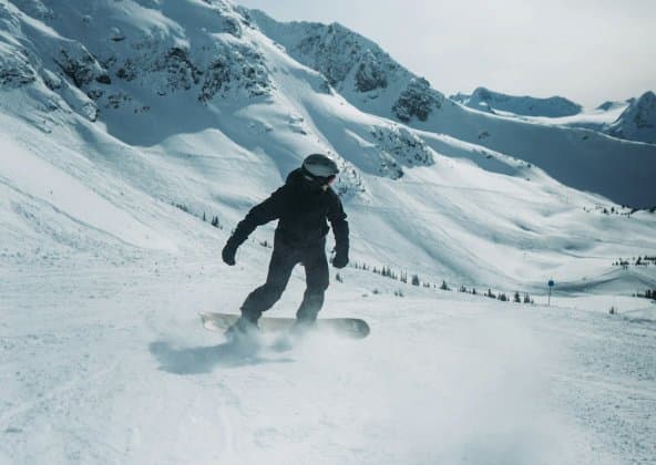 Snowboarder riding down a groomed slope